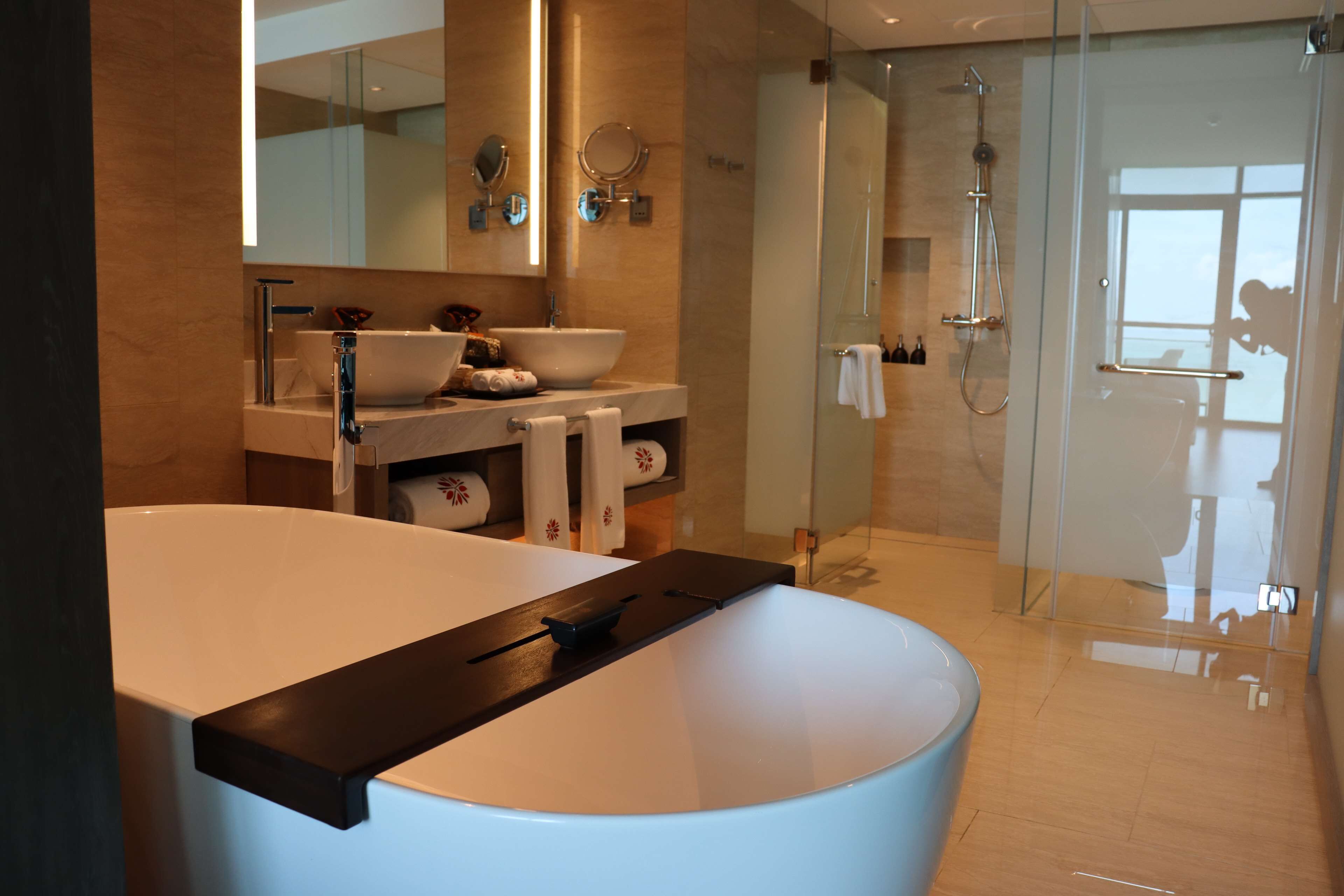 A modern bathroom with a large bathtub, a glass-enclosed shower, and a vanity with a sink and mirrors.