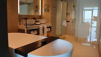A modern bathroom with a large bathtub, a glass-enclosed shower, and a vanity with a sink and mirrors.