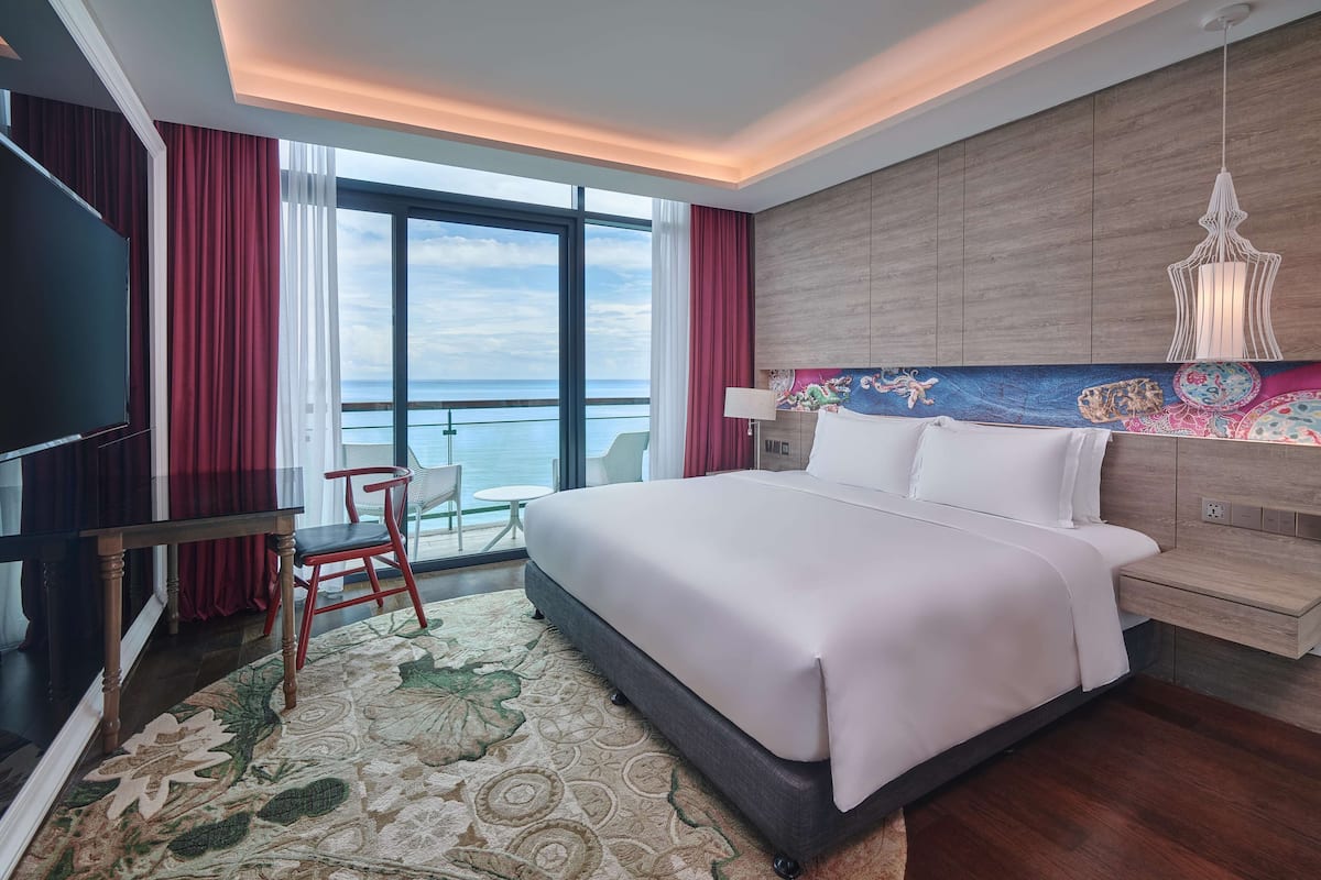 A modern hotel room with a large bed, a TV, a desk, and a chair.