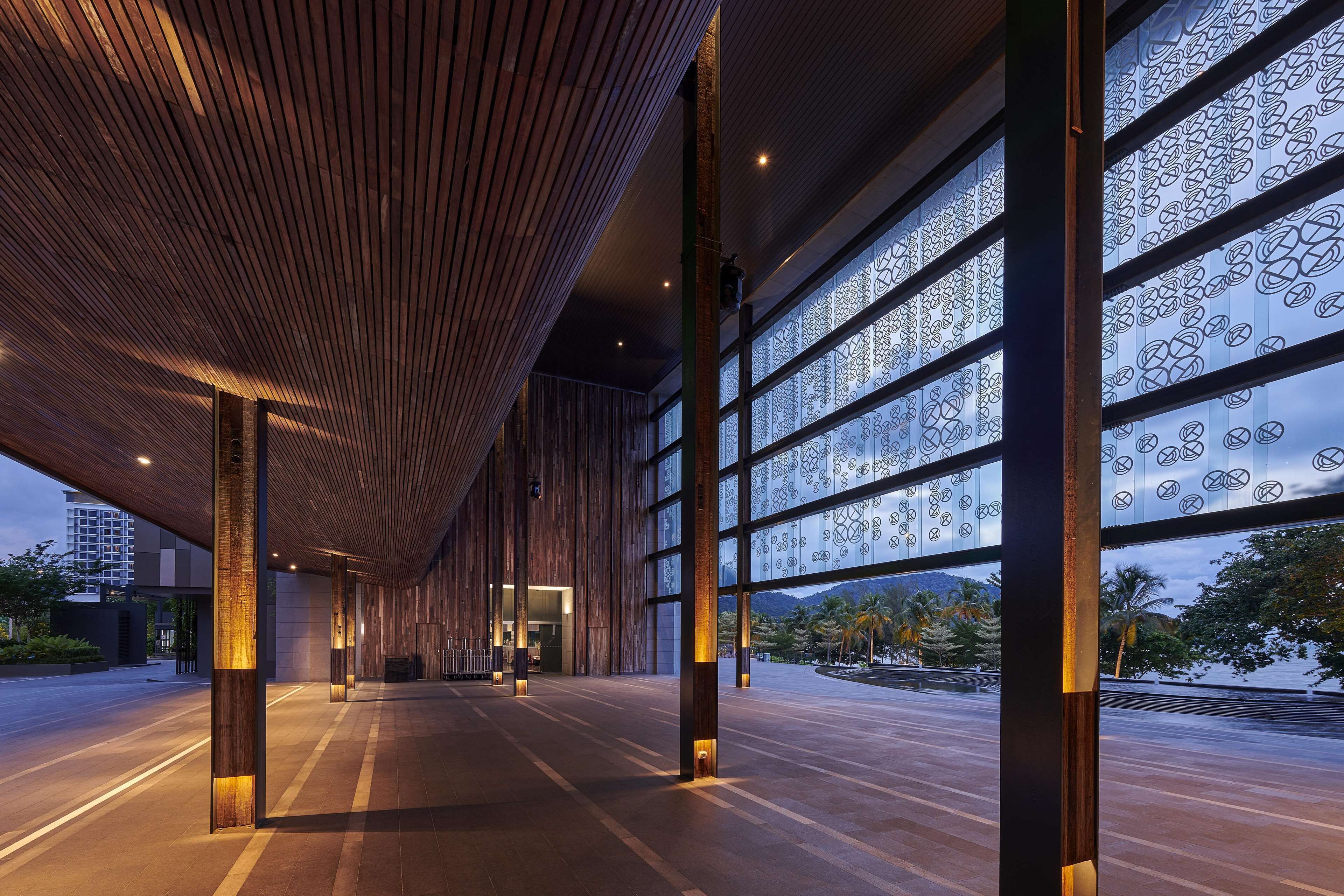 A spacious indoor area with a wooden ceiling and large windows with geometric patterns.