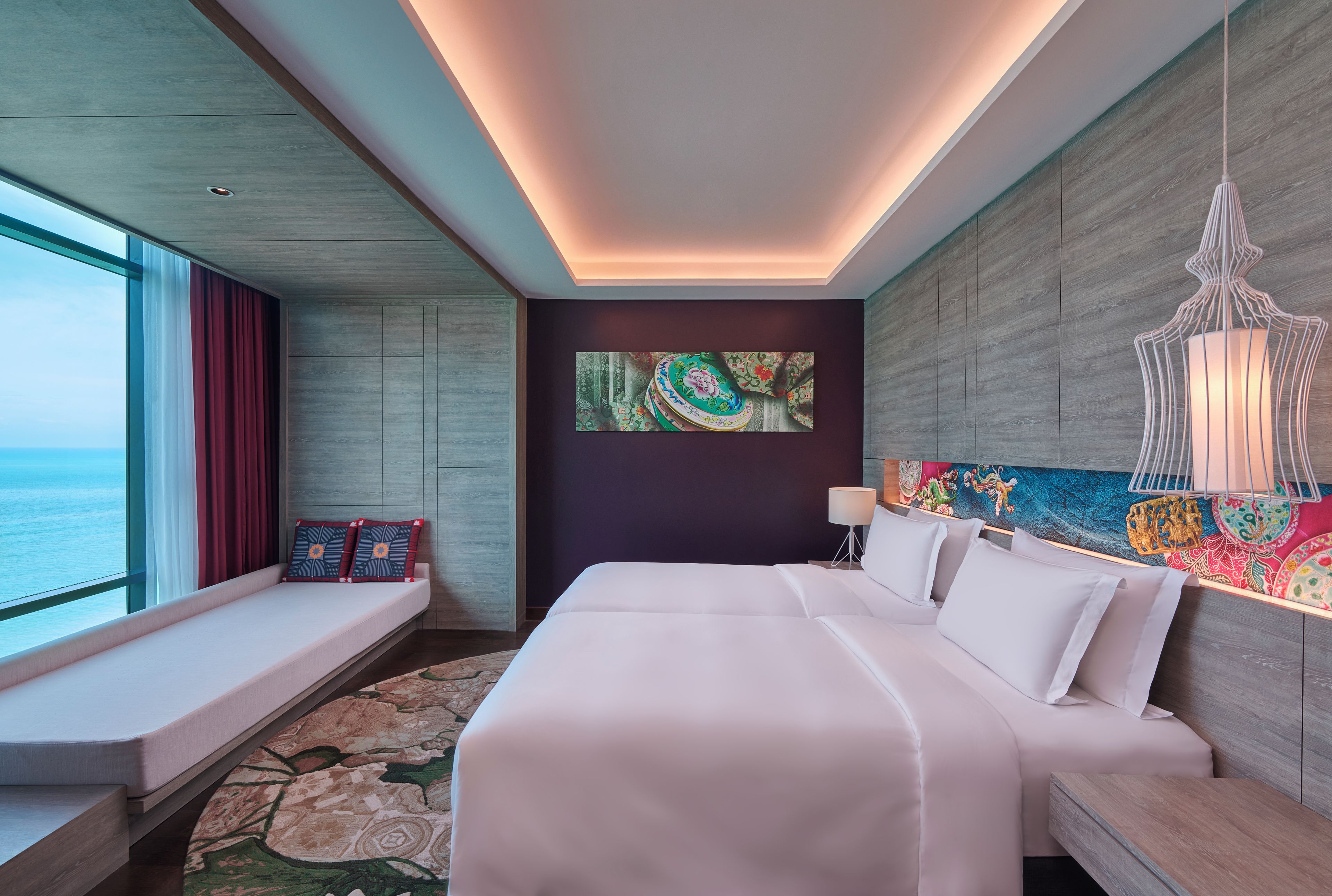 Una habitación de hotel con una cama grande, un área de descanso junto a la ventana y vista al mar.