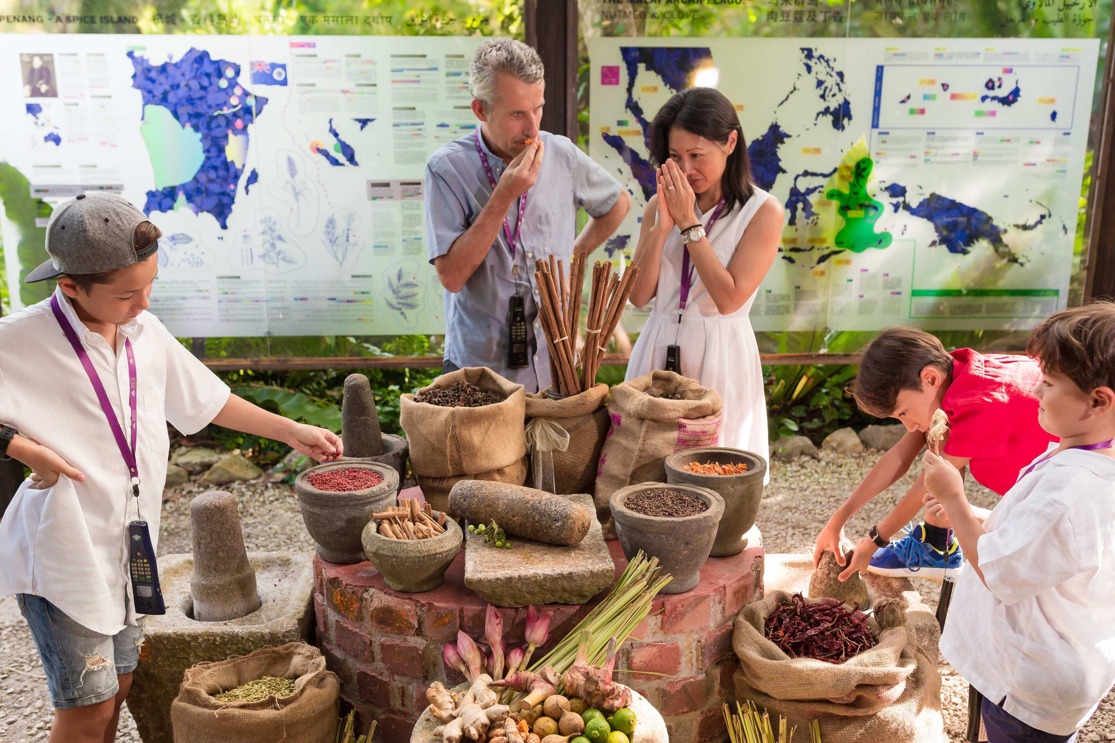 A group of people at an outdoor educational exhibit with various herbs and spices displayed in traditional containers.