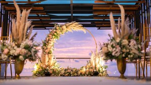 A wedding arch with floral arrangements and a wooden ceiling structure.