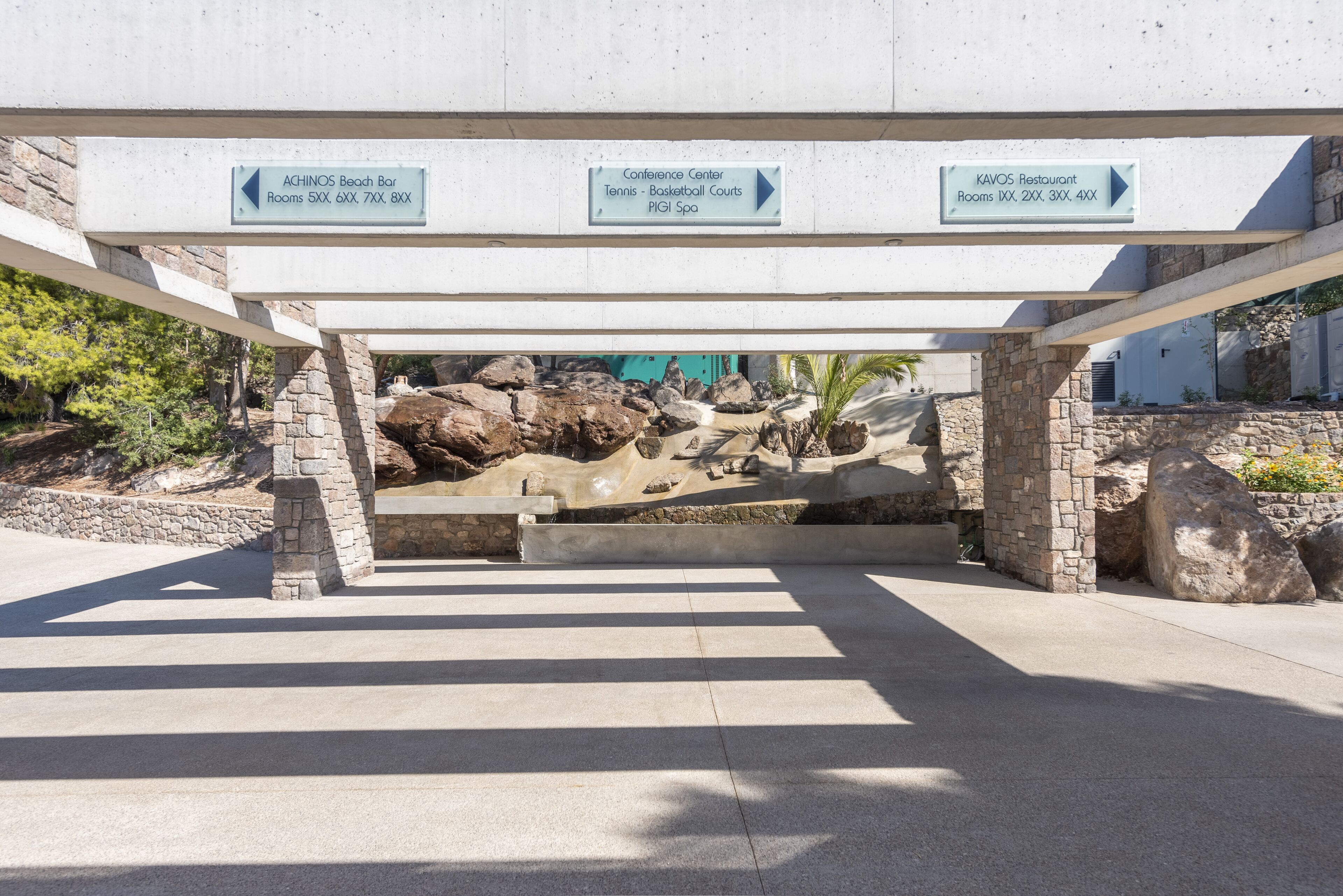 A signpost with directions to ACHINOS Beach Bar, Conference Center, and KAVOS Restaurant.