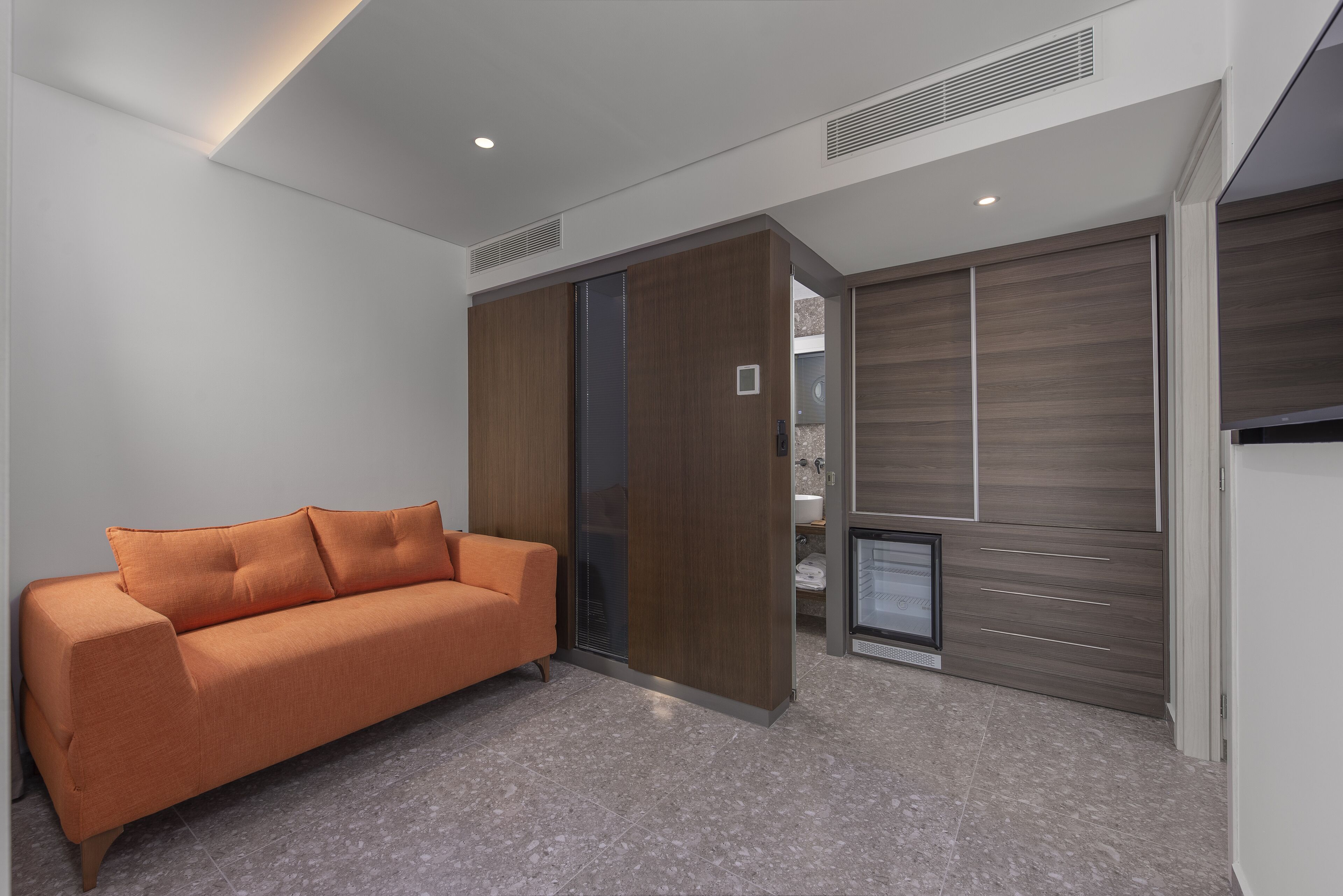 Una habitación moderna con sofá, puertas correderas y televisor empotrado.