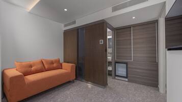 Una habitación moderna con sofá, puertas correderas y televisor empotrado.