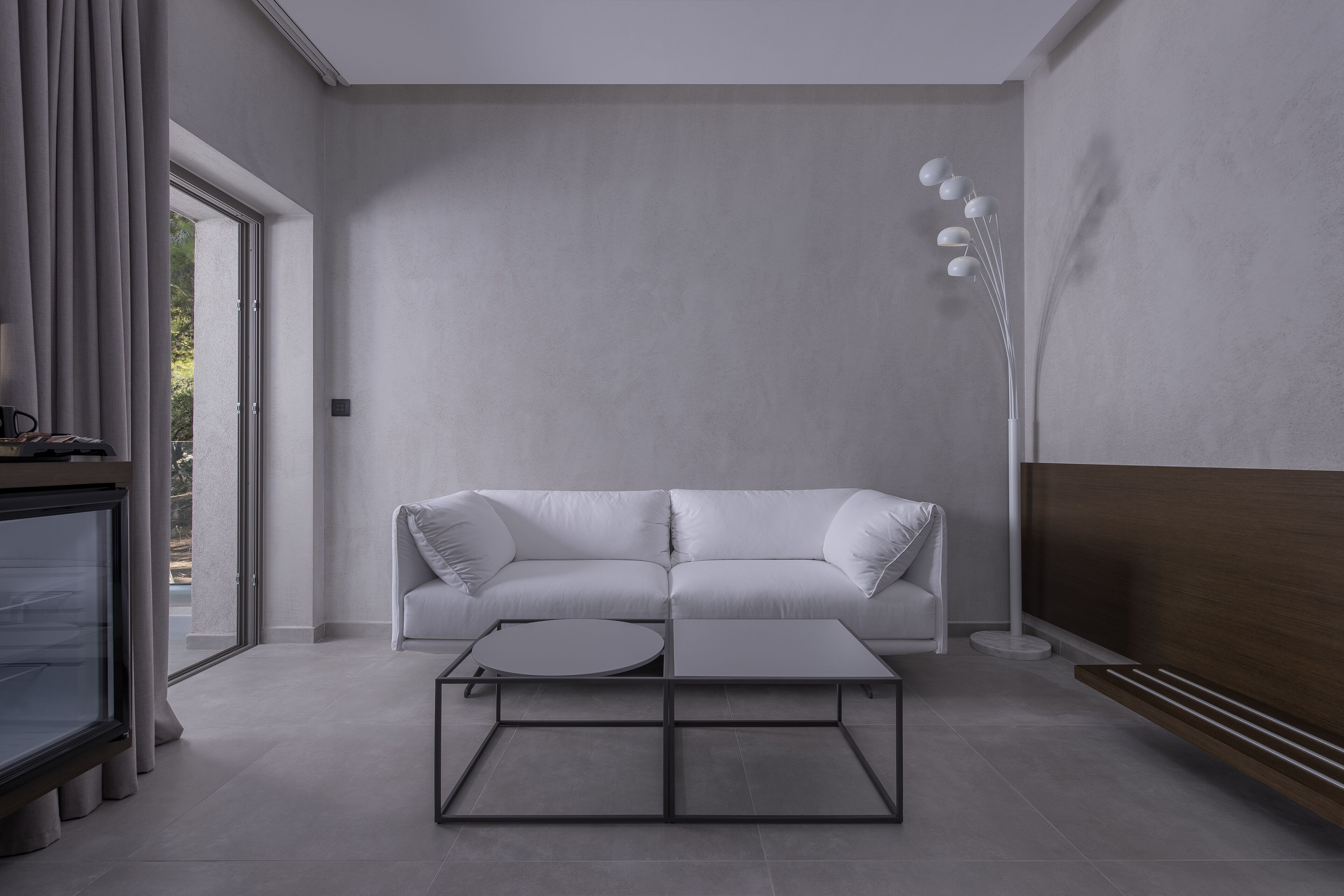 A modern living room with a white sofa, a round coffee table, and a tall floor lamp.