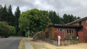 Ein Wohngebiet mit einem Haus, das einen Holzaußenbereich, einen umzäunten Garten und einen großen Baum zeigt.