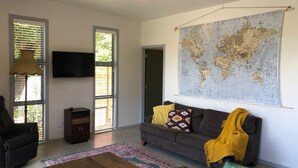 Ein modernes Wohnzimmer mit einer großen Weltkarte an der Wand, einem Sofa mit gelber Decke und einem Fernseher.