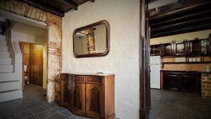 A room with a wooden cabinet, a mirror, a staircase, and a kitchen area. - Casa Amoreira - Quinta Amoreira (Faro)