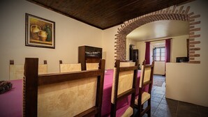 A dining area with wooden chairs and a table, a brick archway, and a painting on the wall. - Casa Amoreira - Quinta Amoreira (Faro)