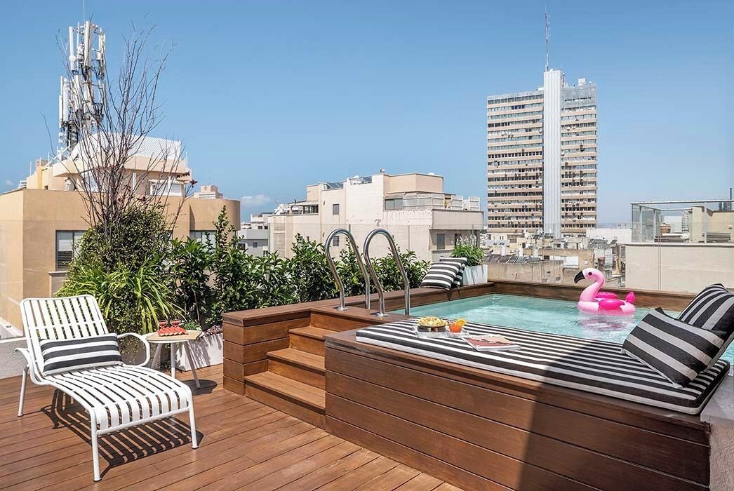 A rooftop pool area with a hot tub, lounge chairs, and a pink flamingo float.