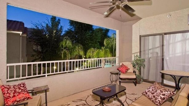 A balcony with a ceiling fan, a sofa, a small table, and a chair. - Arizona Hideaway (Scottsdale)