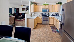 A modern kitchen with wooden cabinets, stainless steel appliances, and a dining area with a table and chairs. - Arizona Hideaway (Scottsdale)