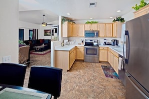 A compact kitchen with wooden cabinets, a microwave, an oven, and a refrigerator.
