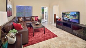 Ein Wohnzimmer mit einem braunen Ledersofa, einem roten Teppich, einem Couchtisch und einem Flachbildfernseher.