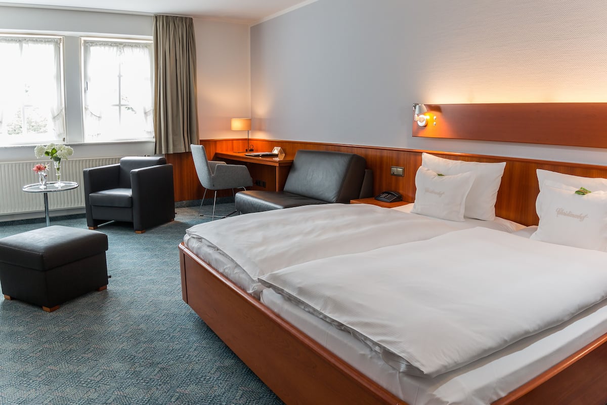 A hotel room with a large bed, a desk, a chair, and a small table with flowers.
