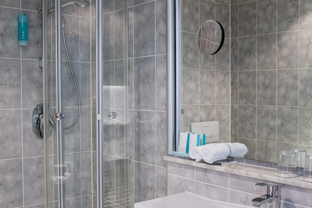 A modern bathroom with a glass-enclosed shower, a white sink, and a mirror.