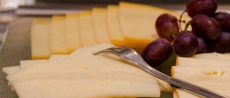 Una tabla de quesos con distintos tipos de queso y uvas sobre un plato verde.