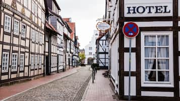 A narrow cobblestone street lined with traditional half-timbered buildings, including a hotel with a sign indicating it is a "HOTEL" and a "No Parking" sign.