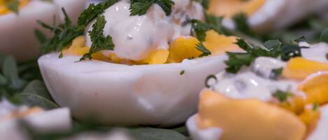 A close-up of a food dish with mango chunks and a creamy sauce, garnished with herbs.