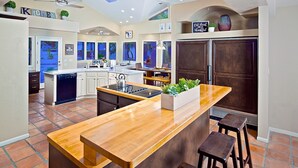 A modern kitchen with a central island, dark cabinetry, and a ceiling fan. - Arizona Desert Haven (Scottsdale)