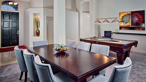 A spacious room with a large wooden dining table surrounded by six upholstered chairs, a pool table, and a wall-mounted artwork. - Kierland Retreat (Scottsdale)