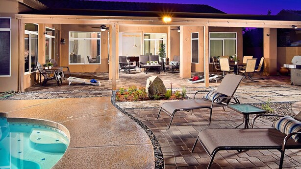 An outdoor patio area with a hot tub, lounge chairs, and a covered seating area with tables and chairs. - Kierland Retreat (Scottsdale)