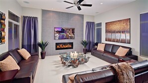A modern living room with leather sofas, a glass coffee table, a fireplace, and a large painting on the wall. - Kierland Retreat (Scottsdale)