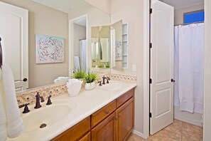 A bathroom with two sinks, a large mirror, and a shower curtain. - Villa Sonoran (Phoenix)