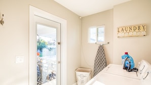A laundry room with a washing machine, a drying rack, and a laundry sign on the wall. - Old Town Retreat (Scottsdale)