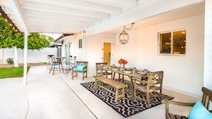 An outdoor patio with a wooden table set for dining, surrounded by chairs and a bench. - Old Town Retreat (Scottsdale)
