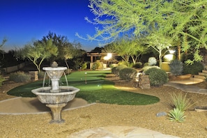 A well-maintained garden with a fountain, a putting green, and various shrubs and trees. - Hacienda Estate (Scottsdale)