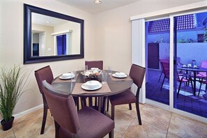 A dining area with a round table, six chairs, and a large mirror on the wall. - Silverado Townhouse (Scottsdale)