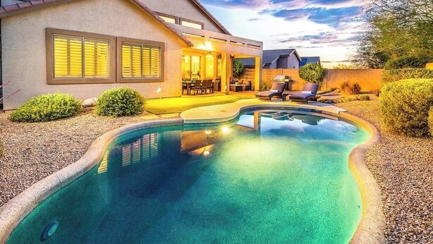 Ett modernt hus med en swimmingpool, utomhusmöbler och en uteplats.