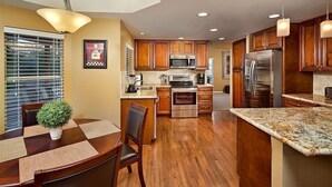 Une cuisine moderne avec des meubles en bois, des appareils en acier inoxydable et un plan de travail en granit.