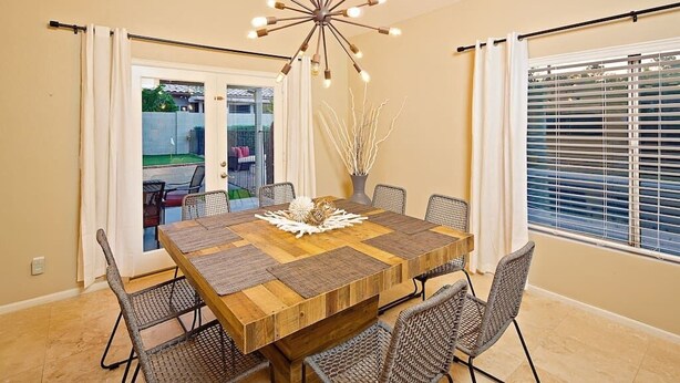 Un espace repas avec une table en bois, des chaises en osier et un lustre moderne.