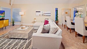 A modern living room with a sofa, coffee table, and dining area. - Kierland Getaway (Scottsdale)