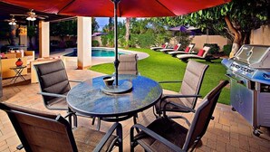An outdoor patio with a round table, chairs, a grill, and a swimming pool. - Kierland Getaway (Scottsdale)