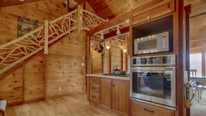 A wooden cabin kitchen with a wooden staircase, a microwave, and a Frigidaire oven.