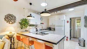 A modern kitchen with a central island, bar stools, pendant lighting, and white cabinetry. - Vibrant 'Casa Paloma' w/ Patio - Near Vineyards! (Patagonia)