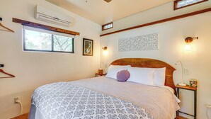 Un dormitorio con una cama grande, cabecera de madera y ventana con vista a árboles.