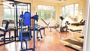 Un gimnasio con diversos equipos de ejercicio, incluyendo una cinta de correr, una elíptica y máquinas de pesas.