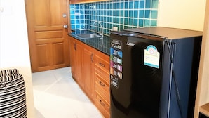 Una cocina con armarios de madera, un refrigerador negro, un microondas y salpicadero con azulejos azules.