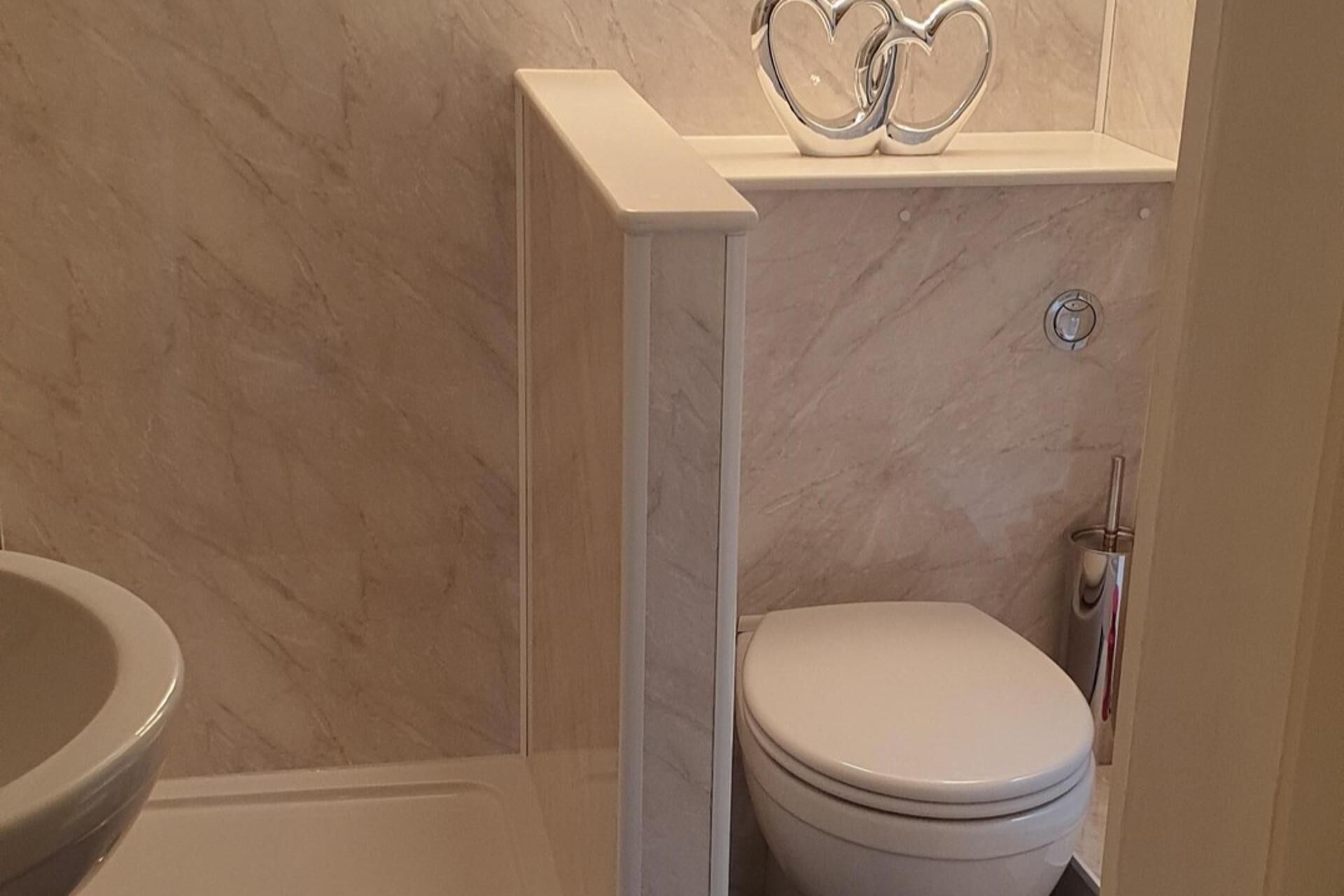 Une salle de bain avec un mur en marbre, des toilettes et un bidet.