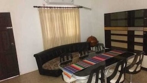 A dining area with a black sofa, a dining table with a colorful striped tablecloth, and a black chair. - Chantal House Sleeps 8 With Garden (Windsor Castle)
