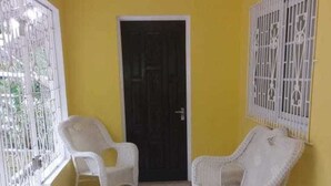 A room with yellow walls, a tiled floor, and white wicker furniture. - Chantal House Sleeps 8 With Garden (Windsor Castle)