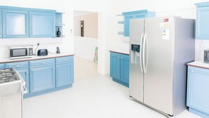 A modern kitchen with blue cabinets, a stainless steel refrigerator, a microwave, and a toaster. - Chantal House Sleeps 8 With Garden (Windsor Castle)
