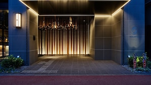 Fachada moderna de un edificio con un letrero que dice 'sequence', luminarias verticales y una pared texturizada.