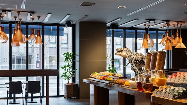 Un café moderno con un mostrador que exhibe diversas opciones de comida y una decoración de dinosaurio.